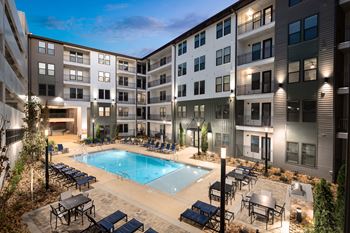 an apartment building with a swimming pool and tables and chairs